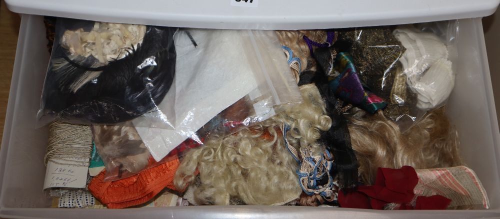A three drawer trolley containing various dolls wigs, lengths of ribboning, braiding etc